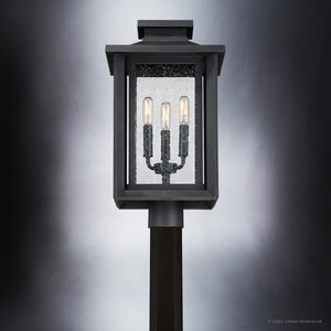 The Urban Ambiance UQL1640 Peacehaven Collection outdoor post light features a black lantern design with seeded glass and three exposed bulbs, shown against a gradient gray background. Marine-grade construction, 19.25''H x 10.75''W.