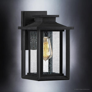 The Urban Ambiance UQL1642 Craftsman Outdoor Wall Sconce from the Peacehaven Collection features a natural black finish, clear seeded glass, marine-grade construction, and visible vintage-style bulb for a vintage-inspired look.