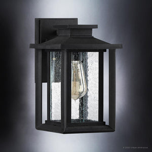 The Urban Ambiance UQL1642 Craftsman Outdoor Wall Sconce, from the Peacehaven Collection, features marine-grade construction, a natural black finish, clear textured glass, and an exposed bulb in a vintage-inspired rectangular design. 11''H x 6.75''W.