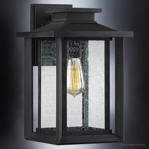 The Urban Ambiance UQL1643 Craftsman Outdoor Wall Sconce, 14''H x 8.75''W, from the Peacehaven Collection features a natural black finish and marine-grade construction, shown with clear glass and a visible bulb on a gray wall.