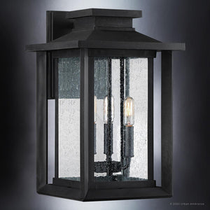 The UQL1644 Craftsman Outdoor Wall Sconce by Urban Ambiance features a natural black finish, seeded glass, and two visible bulbs—offering vintage style and marine-grade durability for timeless exterior appeal. From the Peacehaven Collection.