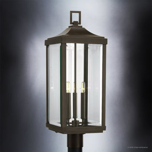 Standing elegantly against a gradient background, the Urban Ambiance UHP1190 Colonial Outdoor Post / Pier Light from the Calderdale Collection showcases its timeless charm with a classic silhouette, three candle-style bulbs, and an Olde Bronze finish.