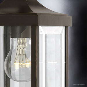 Close-up of a lit incandescent bulb inside the Urban Ambiance UHP1192 Colonial Outdoor Wall Light from the Calderdale Collection, featuring clear beveled glass and an Olde Bronze finish, set against a dark background.
