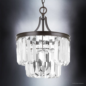 The UHP2467 Cosmopolitan Ceiling Light from the Lille Collection by Urban Ambiance features a two-tiered design with clear angular prismatic glass panels and a metal frame in an Olde Bronze finish, suspended from a chain against a gradient background, creating an elegant centerpiece for your ceiling. Measuring 15-1/2″ x 13-1/8″, this fixture combines sophistication and style.
