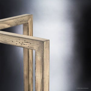 A close-up of two intersecting frames in a weathered galvanized steel finish highlights the Urban Ambiance UHP2743 Modern Farmhouse Pendant Light (12-1/4″ x 10″, Brighton Collection), set against a neutral, blurred background.