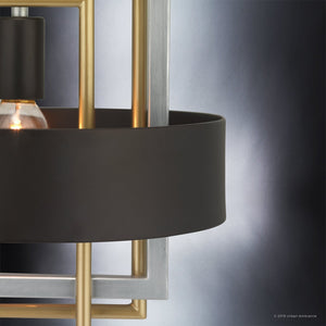 Close-up of the Urban Ambiance UHP2781 Modern Pendant Light from the Vegas Collection, featuring a midnight black cylindrical shade and a stainless steel metallic geometric frame, set against a gradient background.