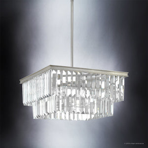 The UHP2885 Cosmopolitan Chandelier from Urban Ambiance’s Lille Collection features a striking two-tiered, square silhouette measuring 11″ x 20-1/8″. Suspended from a sleek metal rod in an antique silver finish, its array of rectangular clear glass prisms beautifully reflects light against a dark gradient backdrop—an exquisite display inspired by prismatic crystal chandeliers and luxurious decorative lighting.