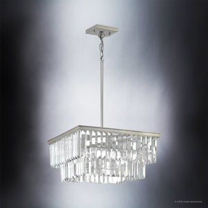 The Urban Ambiance UHP2885 Cosmopolitan Chandelier from the Lille Collection features a modern square design with two tiers of hanging prismatic clear glass prisms, set within an antique silver-finished metal frame, and is suspended from the ceiling by a metal rod. The chandelier measures 11″ x 20-1/8″.